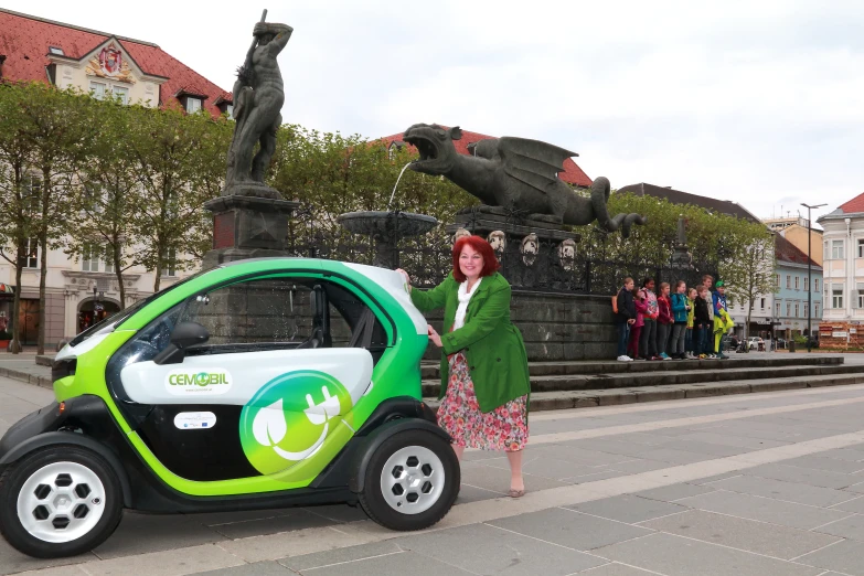 a woman stands next to a small car that's painted green and white