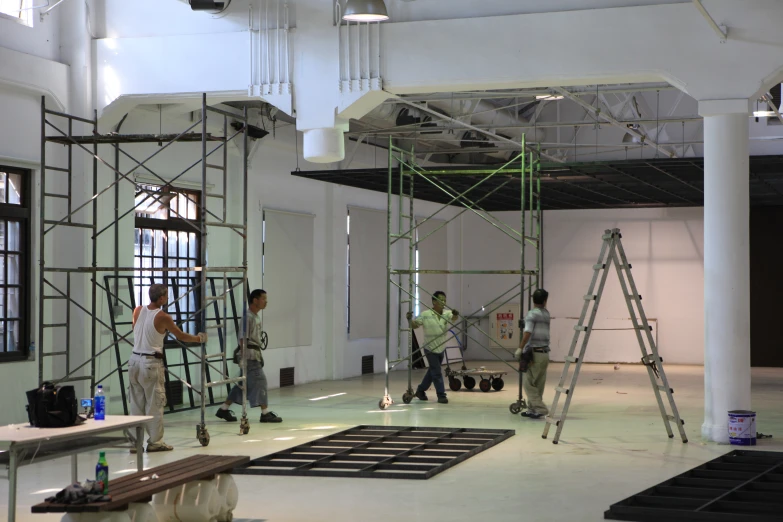 men stand on scaffolding, working on an unfinished structure