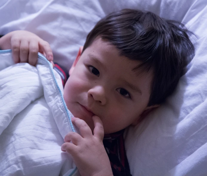 a little boy laying in bed and smiling