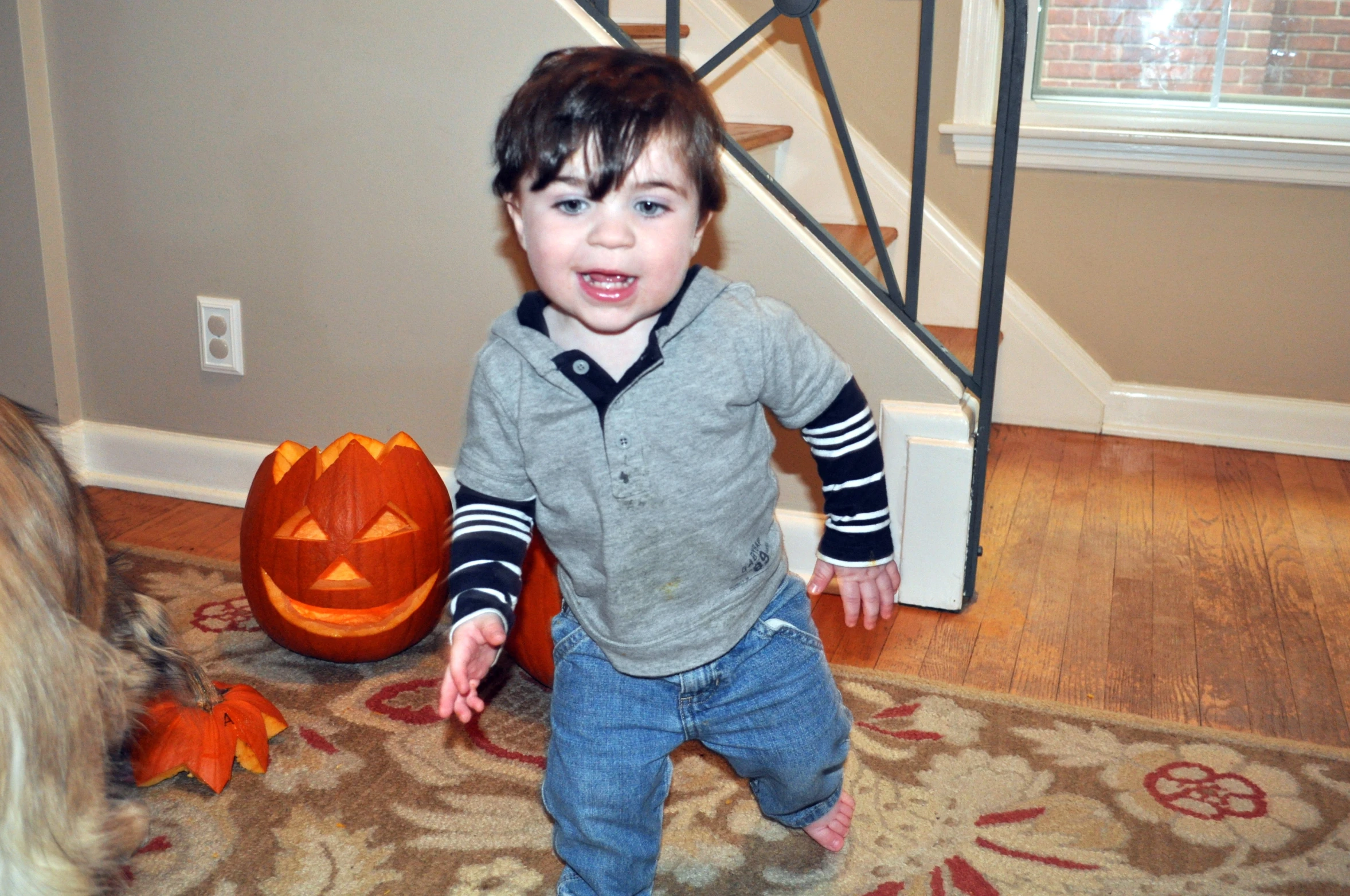 a young child standing next to a carved pumpkin