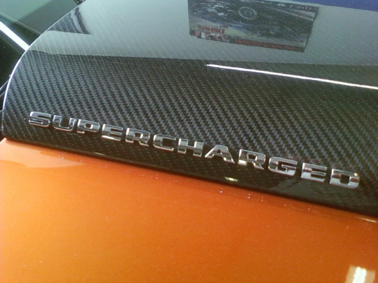 the badge on the front of an orange sports car