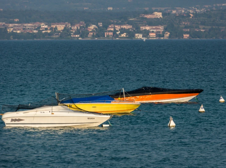 three boats on water with mountains and town in background