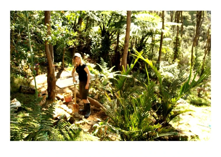 a woman is standing in the forest next to some trees