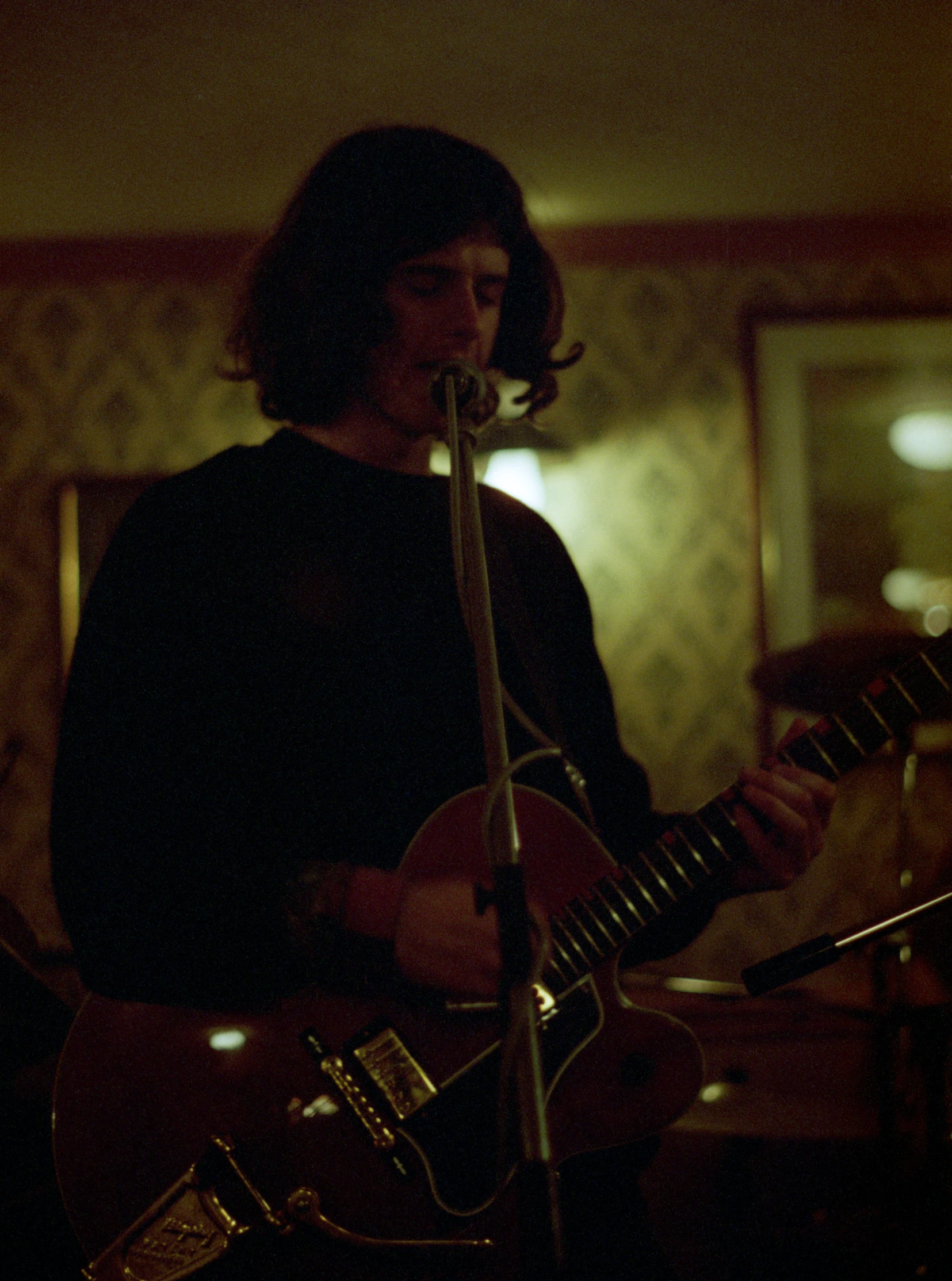 a man playing guitar in front of microphone