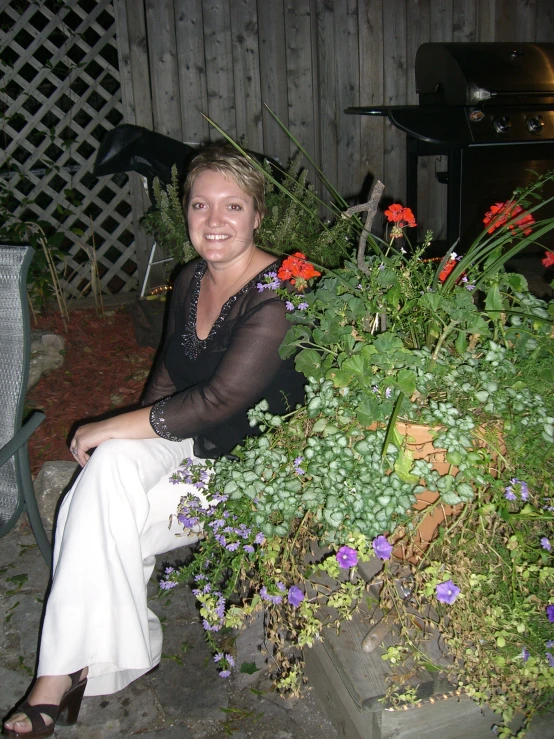 a lady sitting on steps smiling in front of some flowers