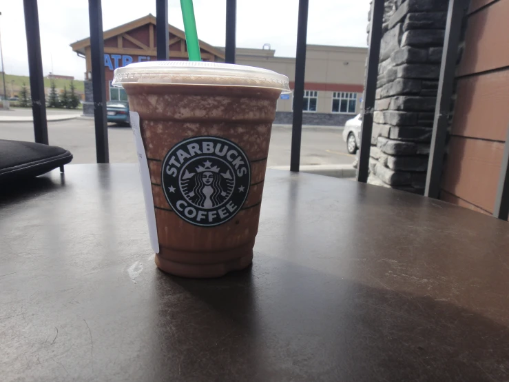 a cup with brown coffee sits on the table outside a restaurant