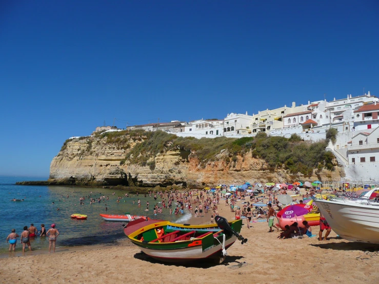 a beach with people and boats sitting on top of it