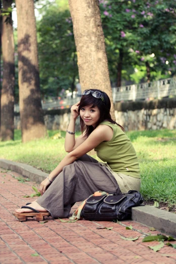 a girl wearing a green shirt is sitting on the sidewalk