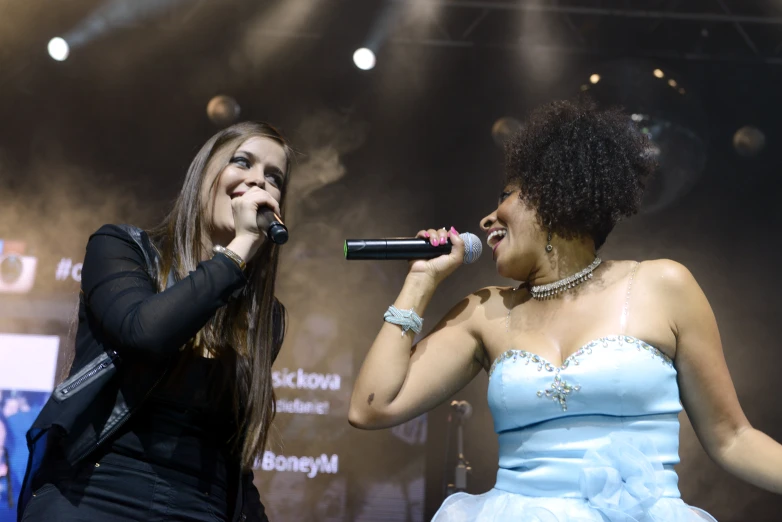 two girls singing at a concert with a microphone