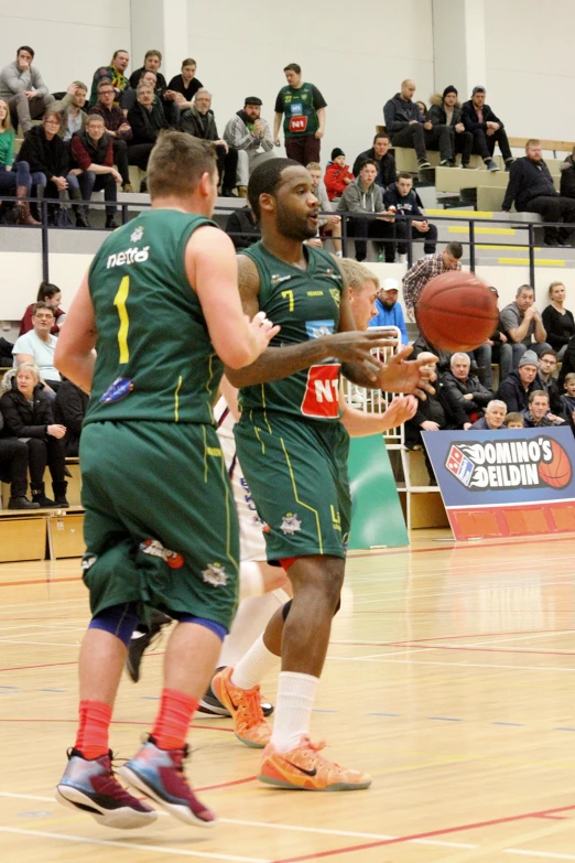 two young men in green jerseys and orange shoes playing basketball
