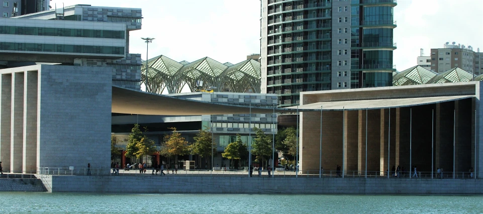 there are people walking on the shore near tall buildings