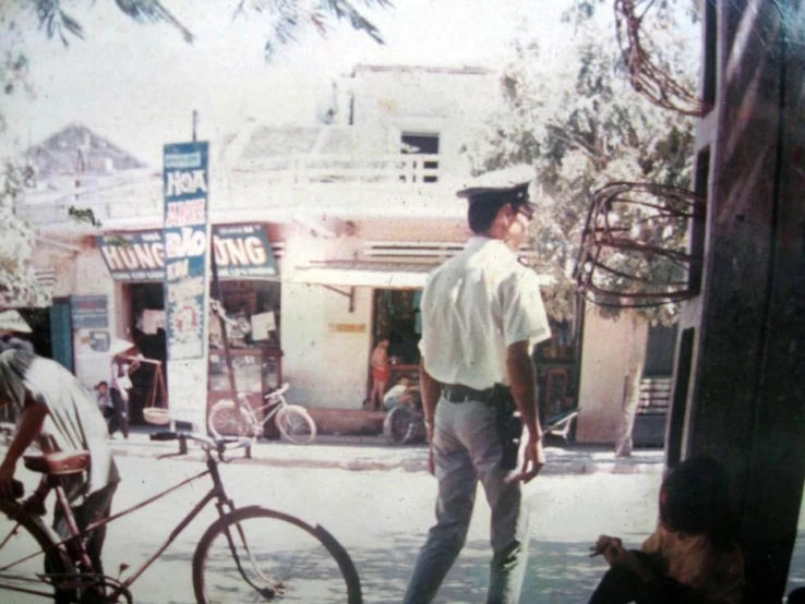 an old po of a man in uniform standing on a sidewalk