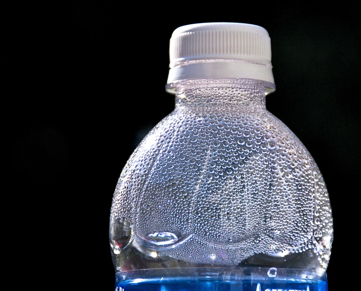 an empty water bottle is sitting in front of a black backdrop