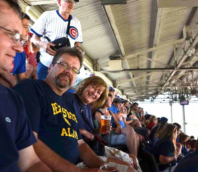 people sitting down at a sporting event and some holding beers