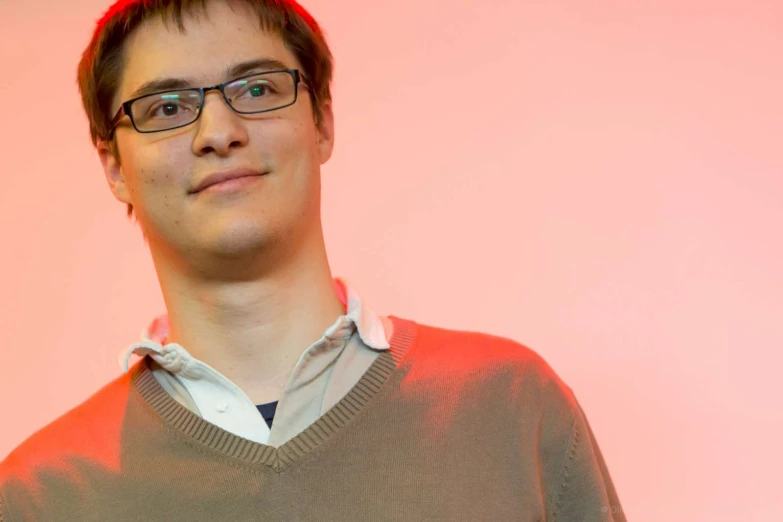 a man in glasses smiles as he poses for a picture