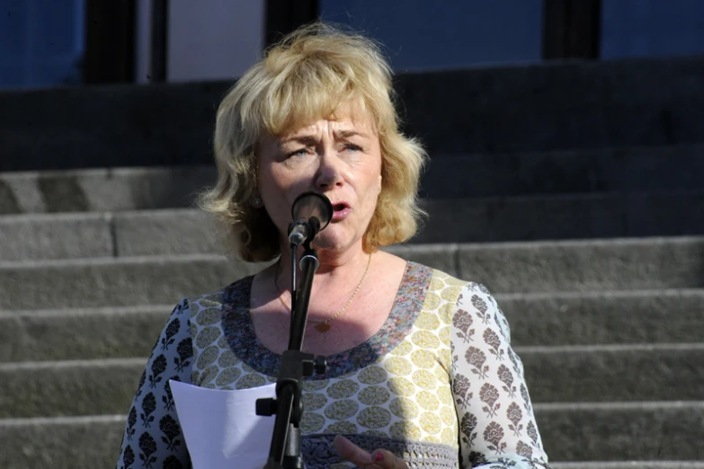 a woman standing at a podium holding a microphone