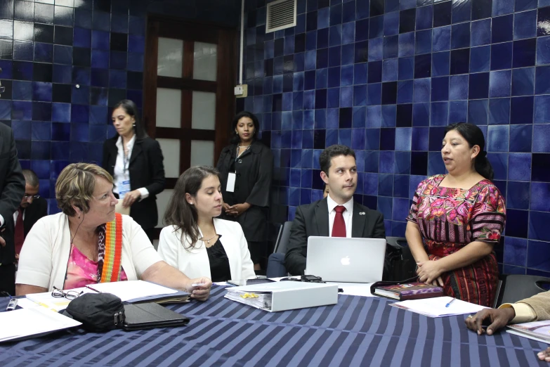 a group of people sitting at a table with laptops