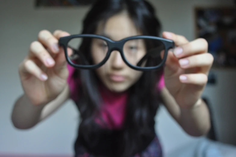 a girl wearing black glasses with her reflection in her eyes