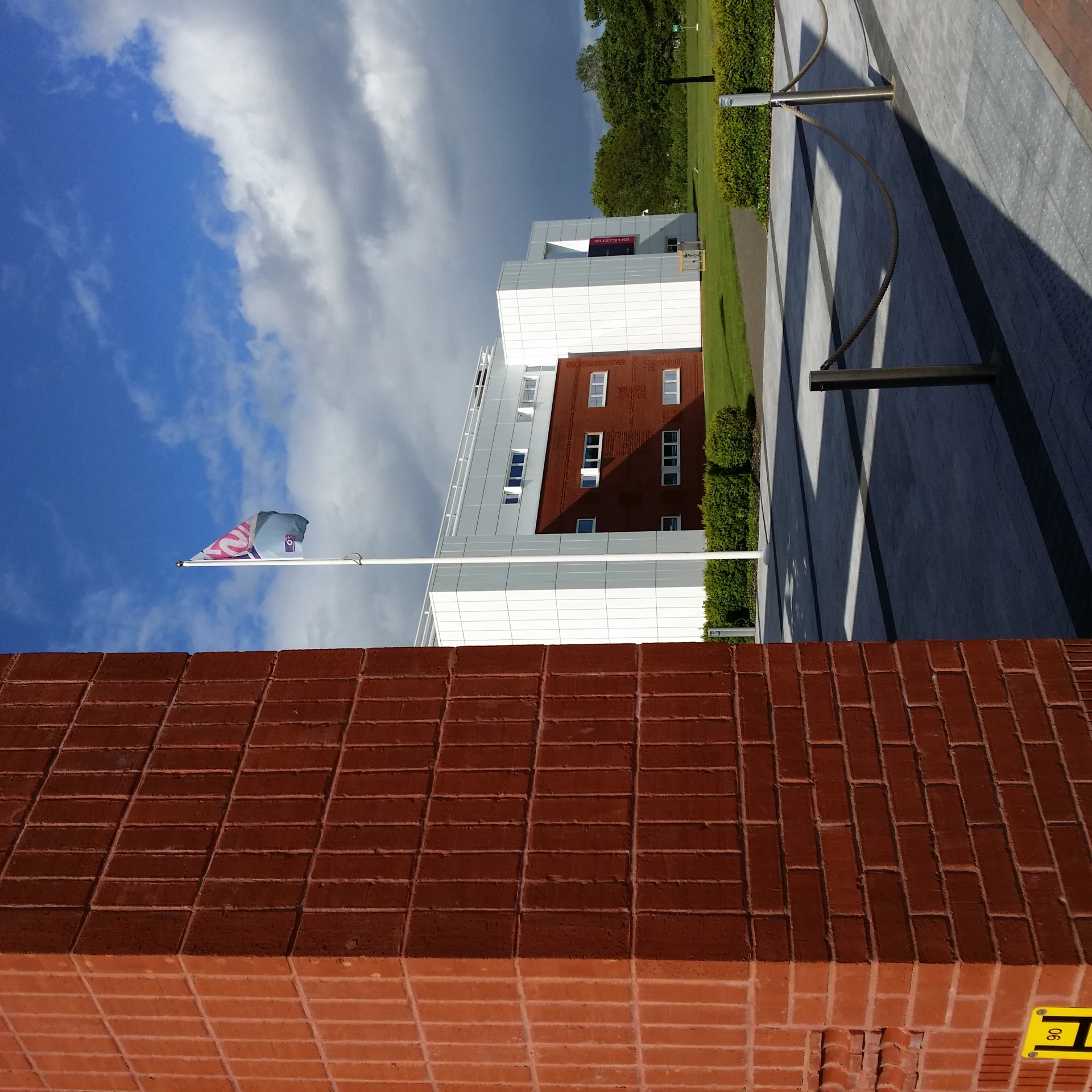 a flag pole standing next to a red brick building