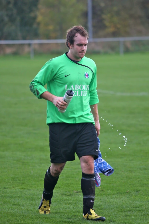 a person wearing a green jersey and black shorts on grass