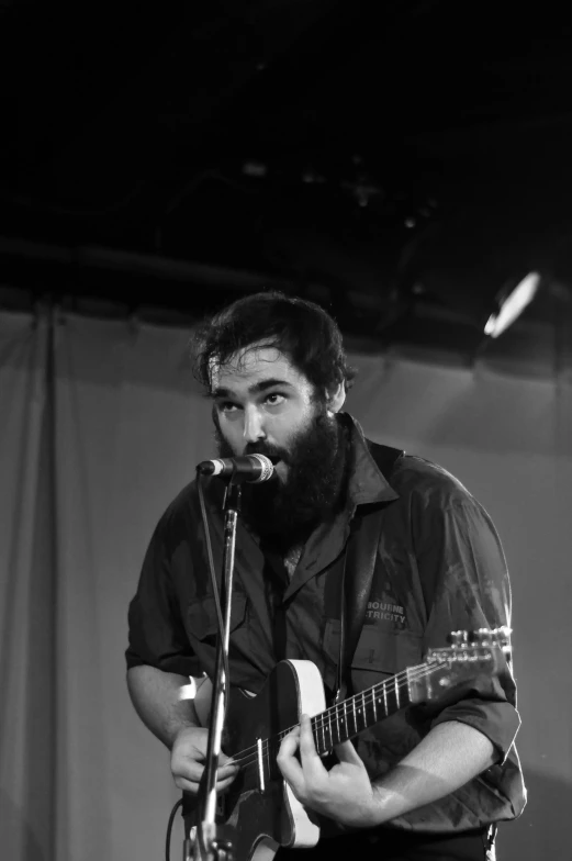 the bearded man is singing into a microphone