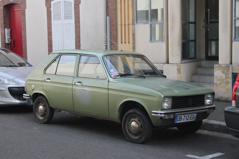 a small light green car parked next to another car