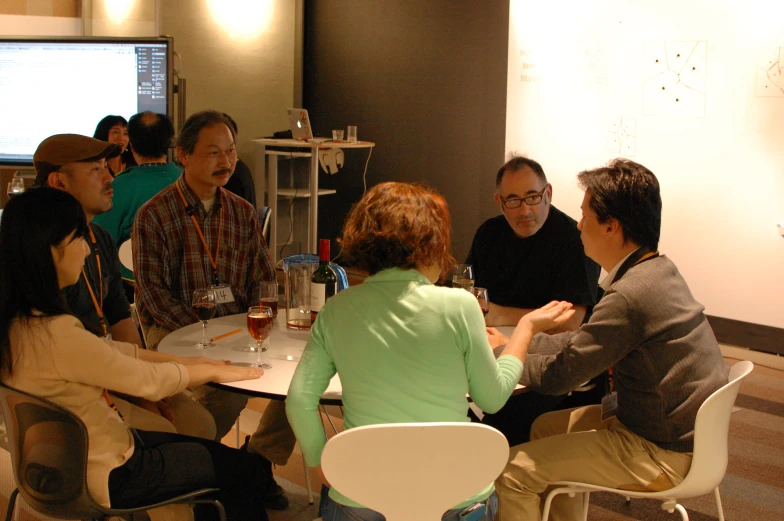 people sitting around a table with one woman holding a wine glass