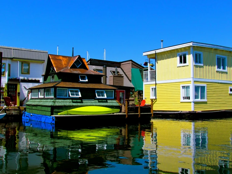 several buildings sit along side of the water and a houseboat is parked on the water
