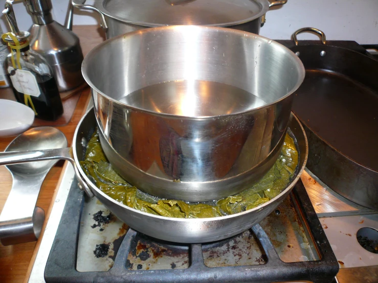 a metal pan filled with food and next to metal pans on a stove