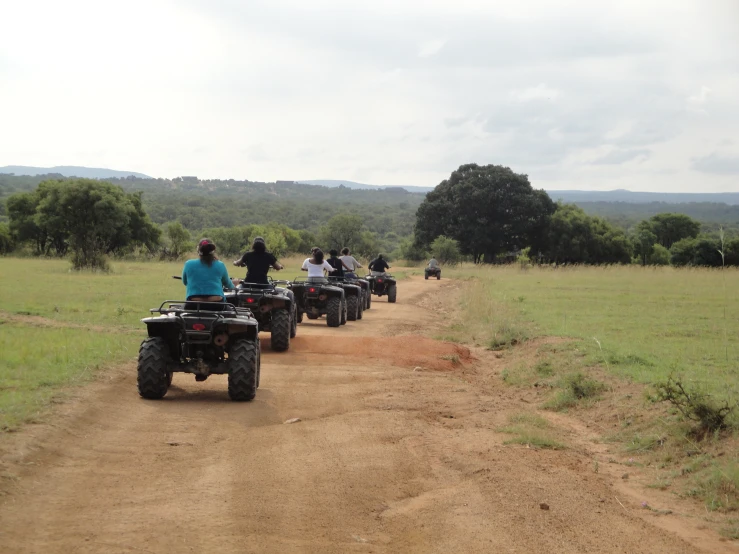 some people riding four wheelers down a dirt road