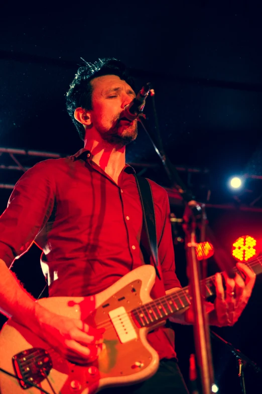 a man playing a guitar on stage with lights