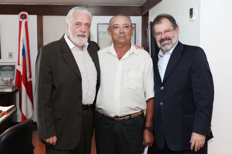 three older gentlemen in business suits posing for the camera