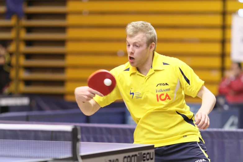 a table tennis player in yellow throwing a ball