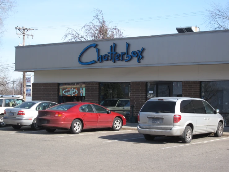 the front entrance of a shop where cars are parked