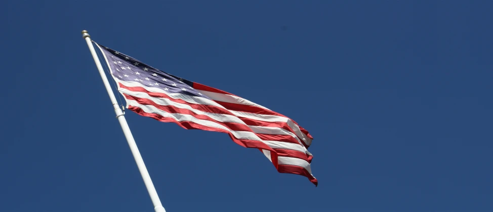 a flag flying high in the air on a windy day