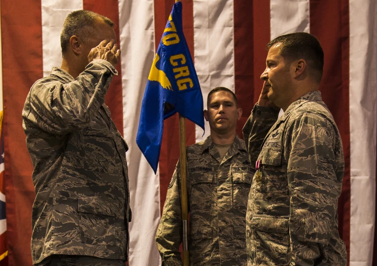 three soldiers are saluting by some flags