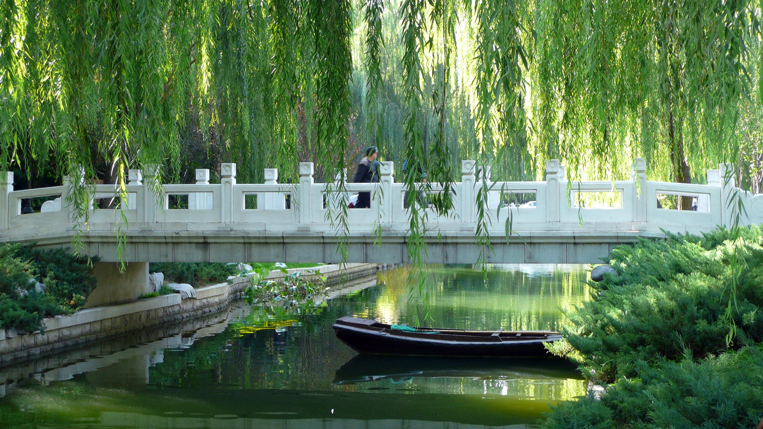 the small boat is traveling down the river near a bridge