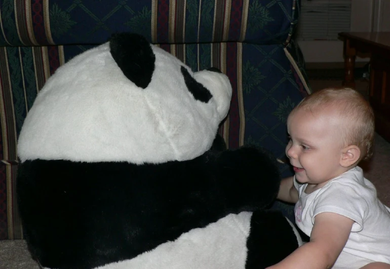 a young baby boy is looking at a giant panda bear