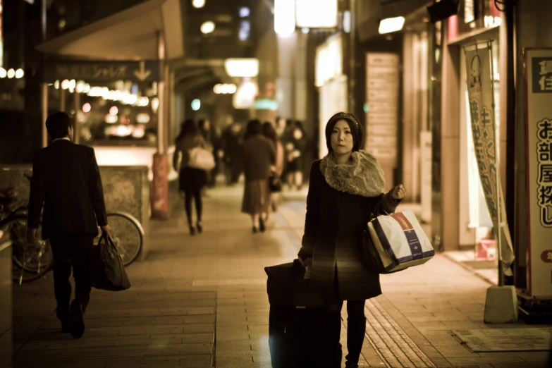 a woman walking down a sidewalk holding a shopping bag