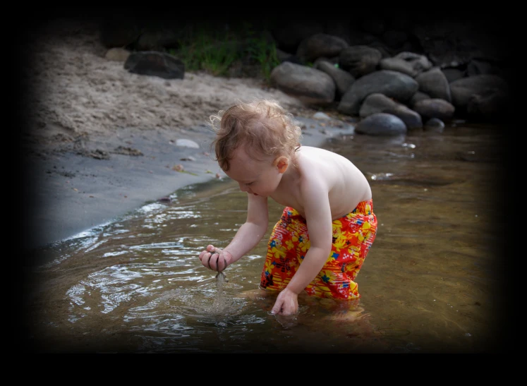 a toddler in the water and his shirt is holding soing