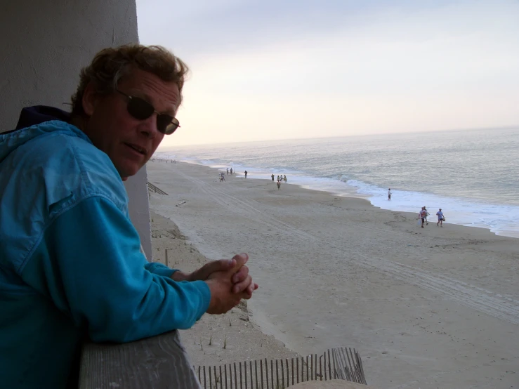 a man with sunglasses standing in front of an ocean view