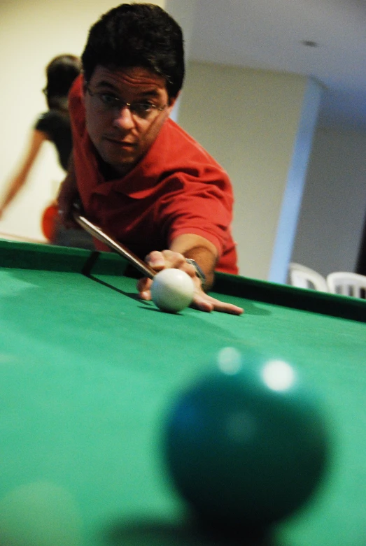 a man with glasses is playing a game of pool