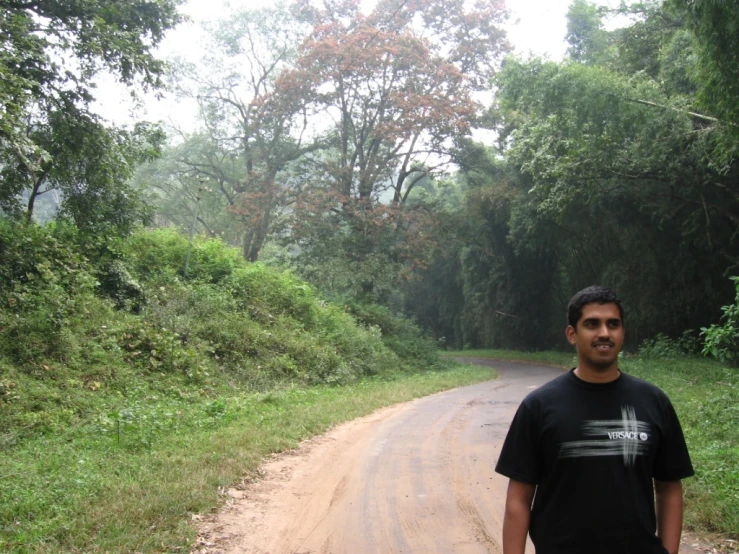 a man stands next to the road on a dirt road