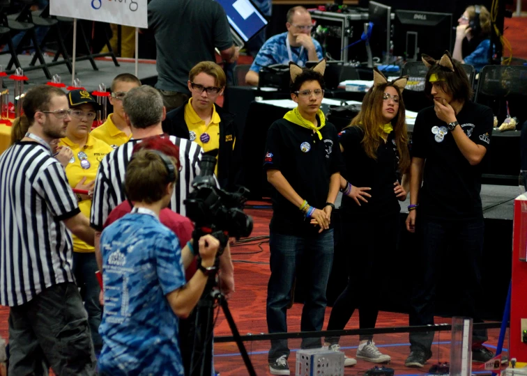 the woman with the striped black dress is being filmed by an referee