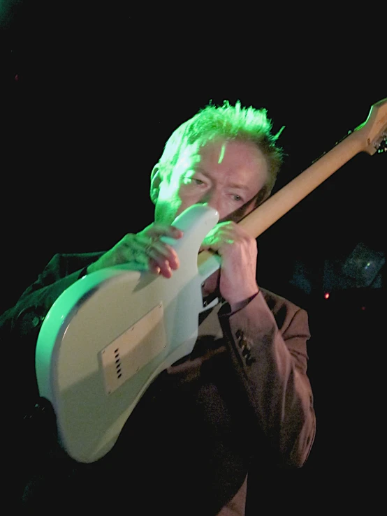 a man holding a green electric guitar in front of his face