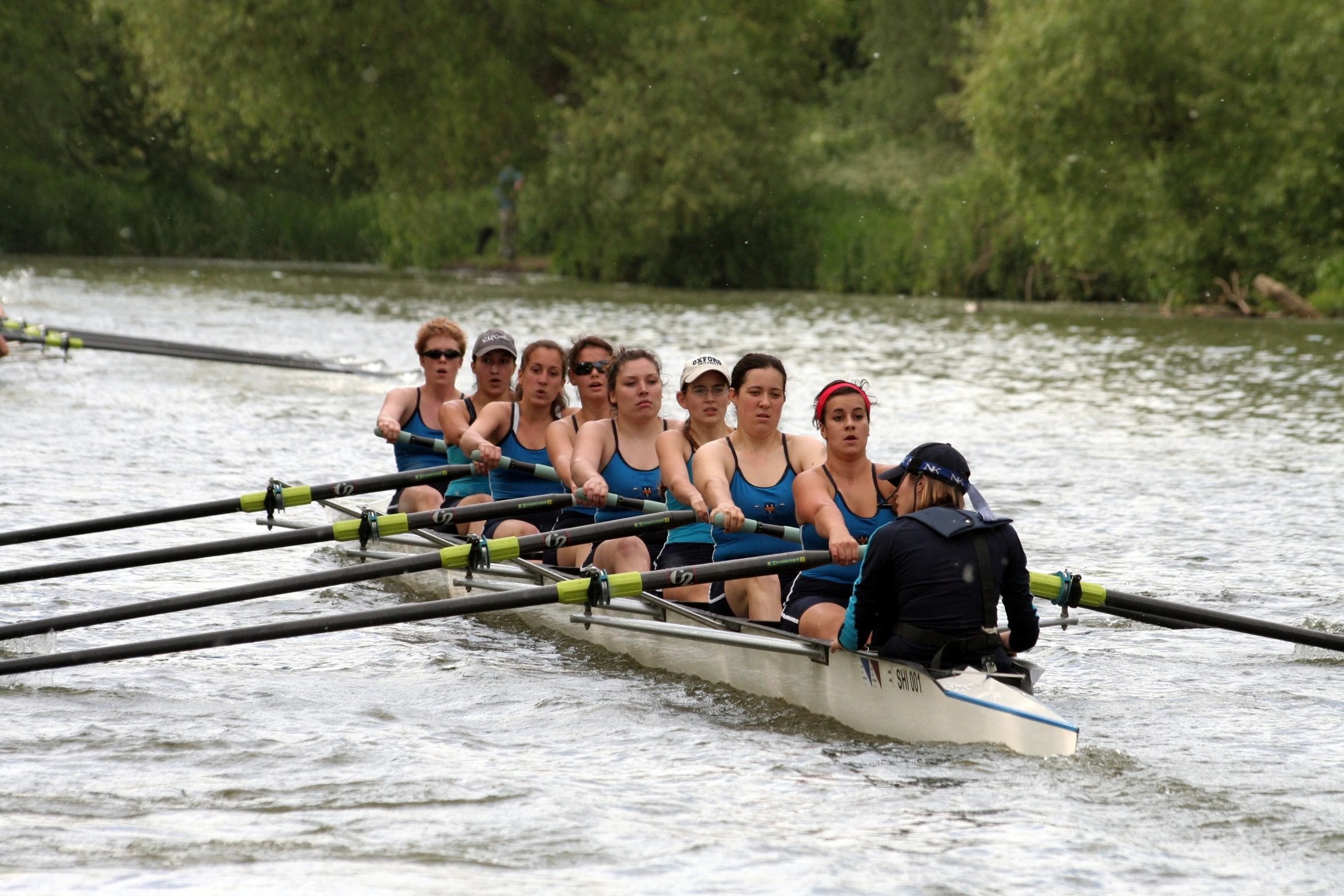 many people wearing swim suits in a rowing boat on water