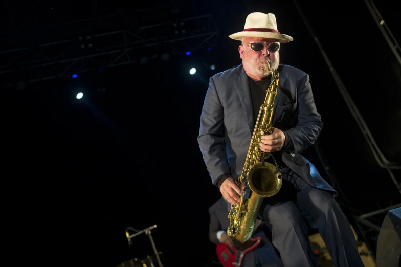 the man in a white hat plays a saxophone