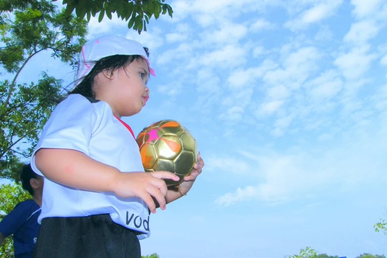 a small child holding up a soccer ball