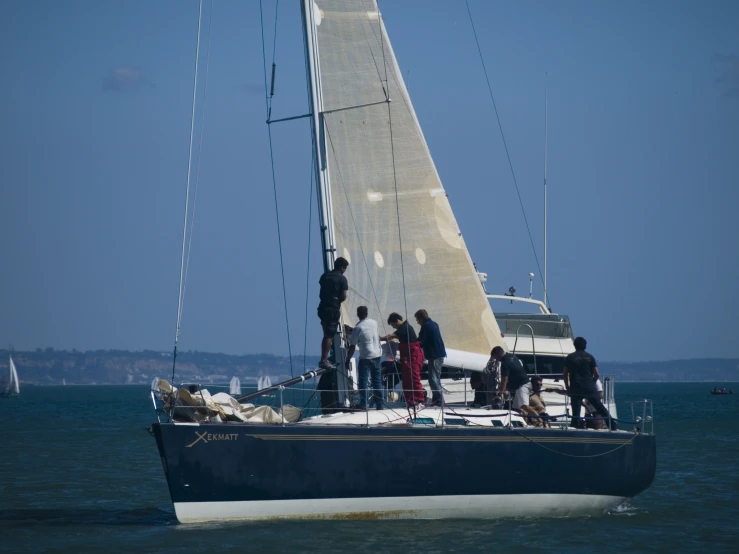 a group of people stand on top of a sailboat in the ocean