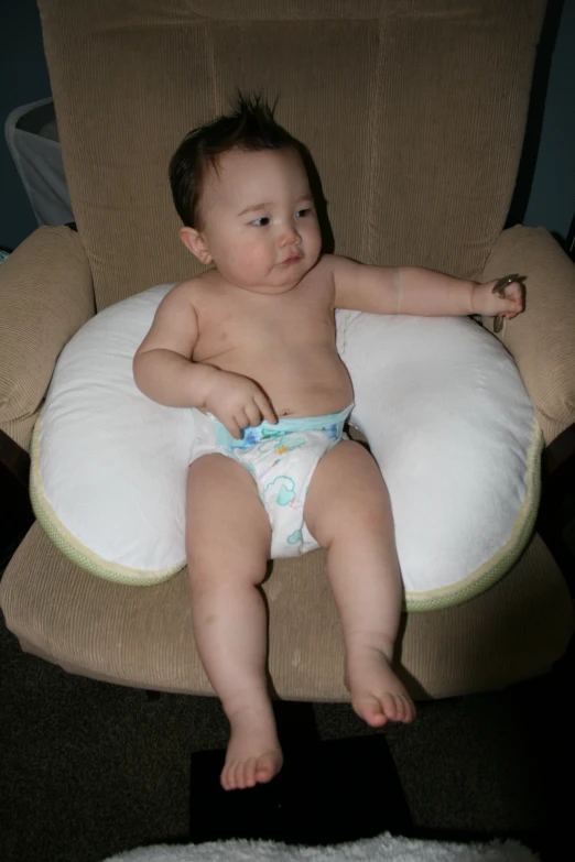 a baby laying in a booster seat with his feet up